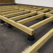 Wooden floor joists on a concrete floor with support pedestals.