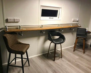 Industrial scaffold board pub bar with galvanized pipe clamps and a long wooden top with three stools.