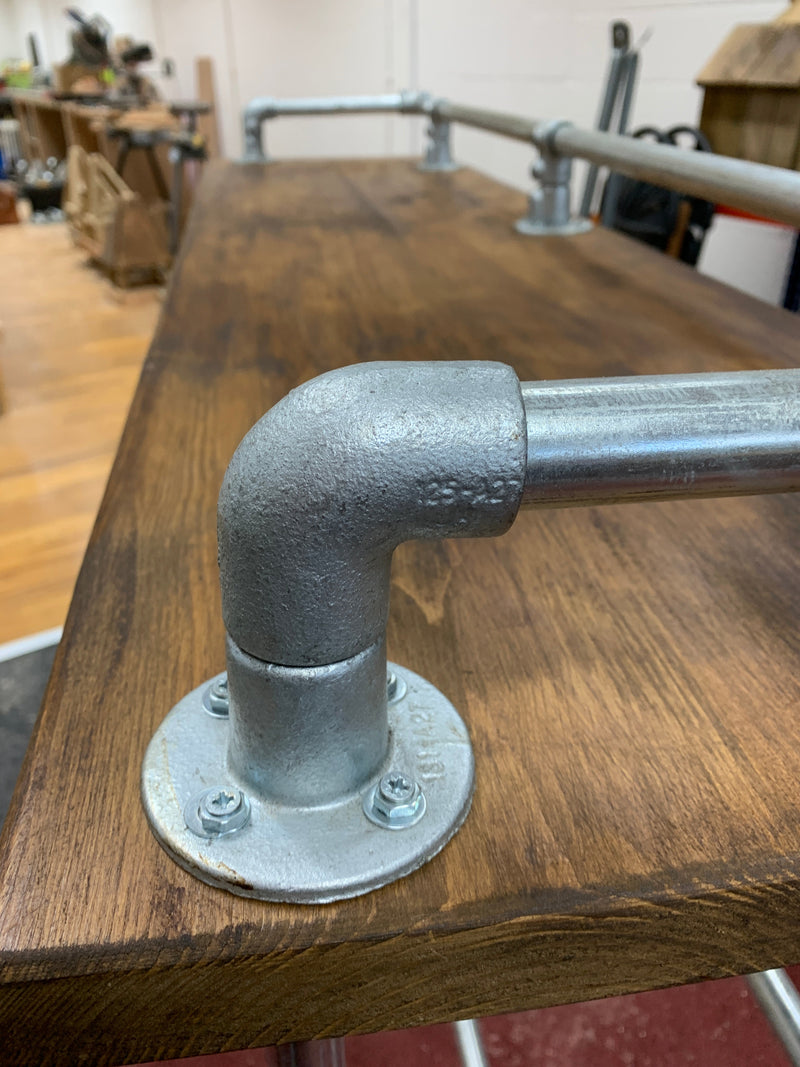 Industrial scaffold board pub or breakfast bar with galvanized pipe railing and elbow joint.