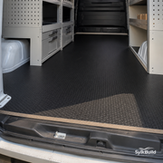 Van interior with storage compartments and a black floor mat, SylkBuild logo visible.