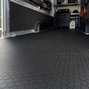 Black textured floor mat in a vehicle interior with tools and equipment.