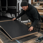 Man working with large black foam sheets in a workshop setting
